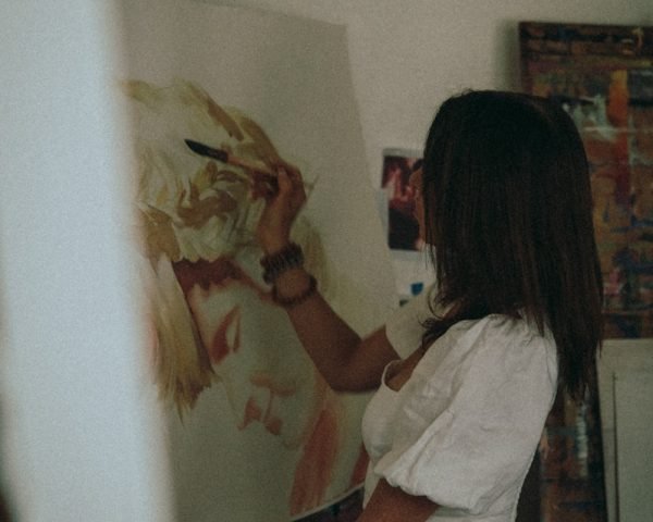 Artista pintando cuadros artesanales con concentración en su taller.