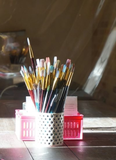 Rincón del taller de arte con pinceles y cuadros artesanales en proceso.