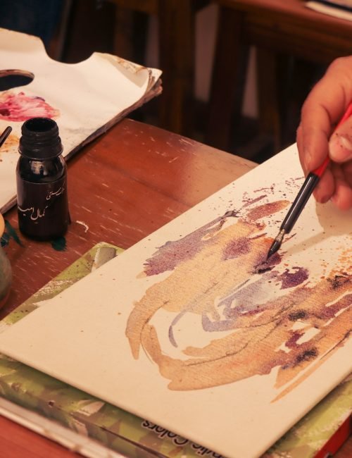 Manos de Gemma trabajando en cuadros artesanales con pincel y lienzo.